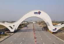 White curved gateway arch over a paved road at Lagos Free Zone, with orange traffic cones guiding vehicles