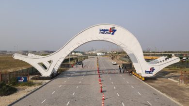 White curved gateway arch over a paved road at Lagos Free Zone, with orange traffic cones guiding vehicles