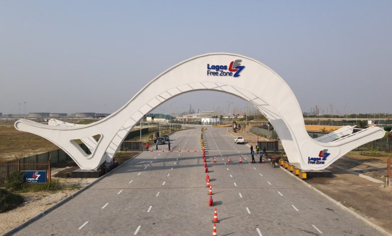 White curved gateway arch over a paved road at Lagos Free Zone, with orange traffic cones guiding vehicles