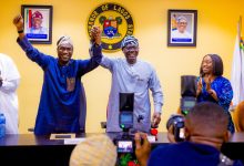 Two men in traditional Nigerian attire raise their clasped hands in celebration at a Lagos State press conference, with the state seal on the wall behind.