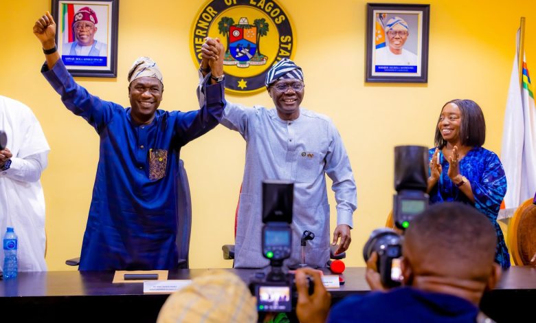 Two men in traditional Nigerian attire raise their clasped hands in celebration at a Lagos State press conference, with the state seal on the wall behind.