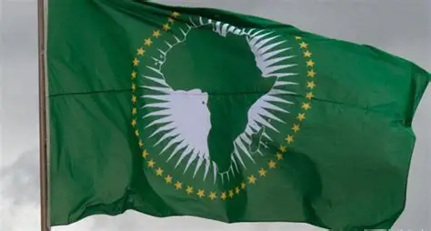 Green flag waving, featuring a white silhouette of Africa inside a ring of gold stars (African Union flag).