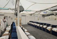 Mina hajj tent - The Times of Abuja Interior of a transport vessel lounge with blue-cushioned seats along the walls and crew members in white in the background.