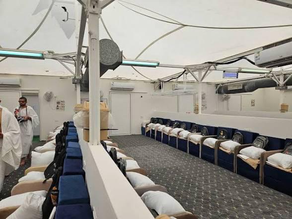 Mina hajj tent - The Times of Abuja Interior of a transport vessel lounge with blue-cushioned seats along the walls and crew members in white in the background.