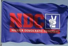 Blue flag featuring the Nigeria Democratic Congress (NDC) logo in red and a white peace/hand sign icon on a blue background.