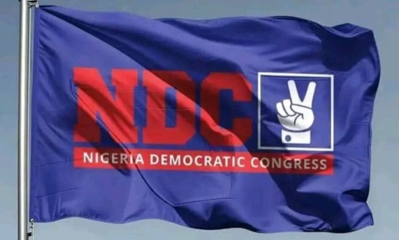 Blue flag featuring the Nigeria Democratic Congress (NDC) logo in red and a white peace/hand sign icon on a blue background.