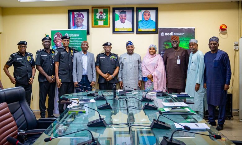 Group of men and women in a conference room posing for a photo, including uniformed officers and civil attendees with banners in the background.