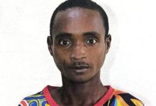 Portrait of a man with short hair wearing a bright, multicolored patterned shirt against a white background, facing the camera.