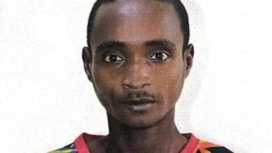 Portrait of a man with short hair wearing a bright, multicolored patterned shirt against a white background, facing the camera.