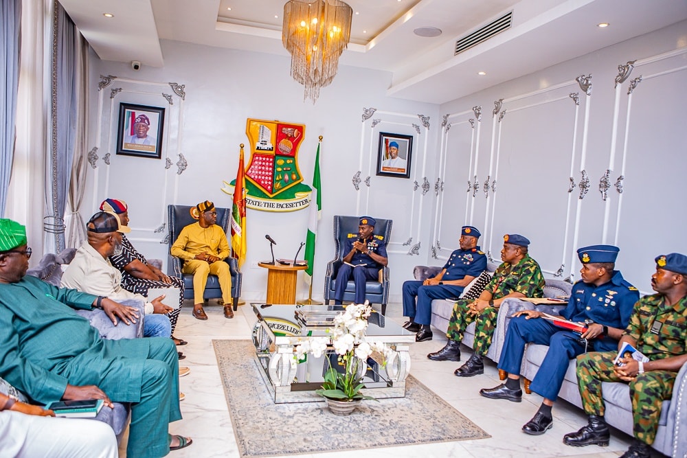 Makinde and NAF officers 3 - The Times of Abuja Formal meeting in a bright government room with dignitaries seated in a semicircle around a central podium.