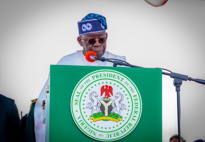President Bola Tinubu 2 - The Times of Abuja Man in traditional attire speaks at a podium adorned with the Seal of the President of Nigeria and a microphone in front of him.