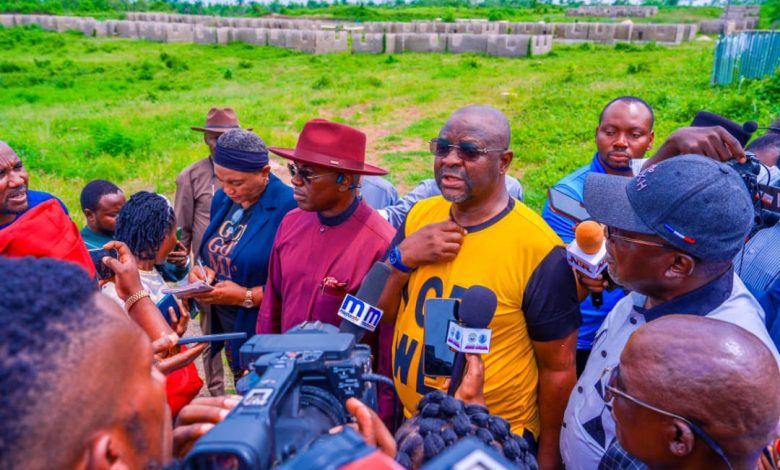 Sunday Dare during the media tour - The Times of Abuja Reporters surround a man in a yellow shirt as he speaks into multiple microphones at an outdoor press conference in a grassy field, with cameras nearby.