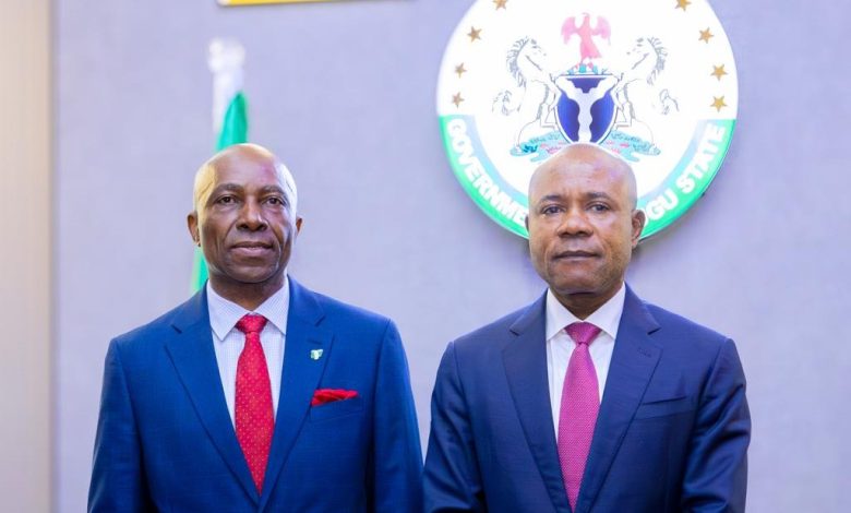 Tax ombudsman and Peter Mbah - The Times of Abuja Two men in dark blue suits pose side by side in front of a round government seal on the wall, for a formal portrait.