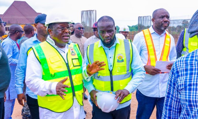 Group of construction workers and officials in high-visibility vests discussing at a site, one man holding a hard hat.