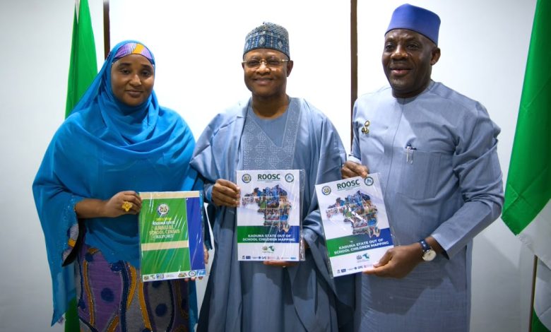 Alausa and Uba Sani - The Times of Abuja Three Nigerians in traditional attire pose together, each holding a ROOSC report on Kaduna State out-of-school children mapping, with green flags in the background.