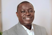 Portrait of a smiling man wearing a light gray blazer and white shirt, facing the camera.