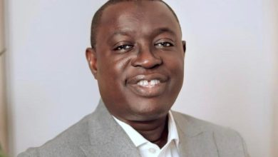 Portrait of a smiling man wearing a light gray blazer and white shirt, facing the camera.