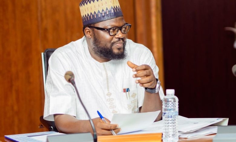 David Daser president and chief executive officer of DBI - The Times of Abuja Man in traditional attire and patterned cap sitting at a desk with papers, speaking and gesturing during a meeting.