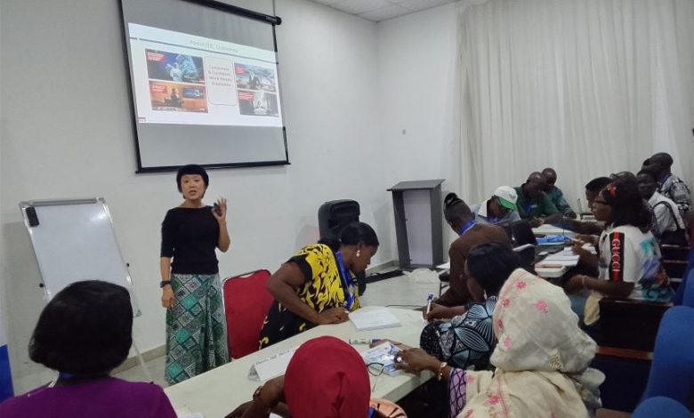FGs TVET training programme - The Times of Abuja Instructor standing at the front of a classroom giving a presentation to a diverse group seated around tables with a projected slide behind her