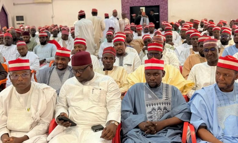 Kwankwasiyya movement - The Times of Abuja Large group of men in traditional white, cream, blue outfits and red caps seated at an indoor formal event.