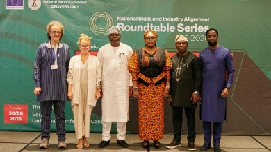 Six diverse professionals posing for a photo in front of a green conference backdrop that reads 'National Skills and Industry Alignment Roundtable Series.'