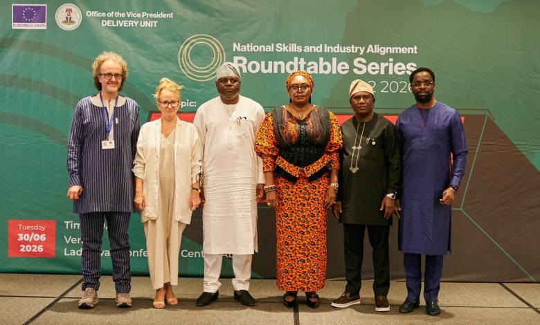 National skills roundtable series - The Times of Abuja Six diverse professionals posing for a photo in front of a green conference backdrop that reads 'National Skills and Industry Alignment Roundtable Series.'