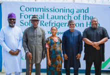 Five people pose in front of a banner that reads 'Commissioning and Formal Launch of the Solar Refrigeration Hub' at an event.