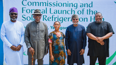 Five people pose in front of a banner that reads 'Commissioning and Formal Launch of the Solar Refrigeration Hub' at an event.
