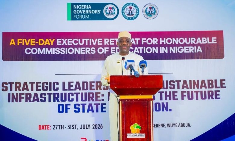 Man in white traditional attire speaks at a podium during a Nigeria Governors' Forum event, with a large banner behind him.