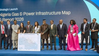 Group of diverse professionals on a blue stage posing with a large Nigeria Gas & Power Infrastructure Map during a strategic launch event.