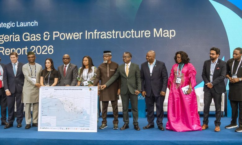 gas and power insfratructure map - The Times of Abuja Group of diverse professionals on a blue stage posing with a large Nigeria Gas & Power Infrastructure Map during a strategic launch event.