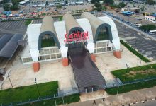 Aerial view of a modern bus terminal with three curved white arches and a covered ramp, signage reads 'Central Business District Bus Terminal'.