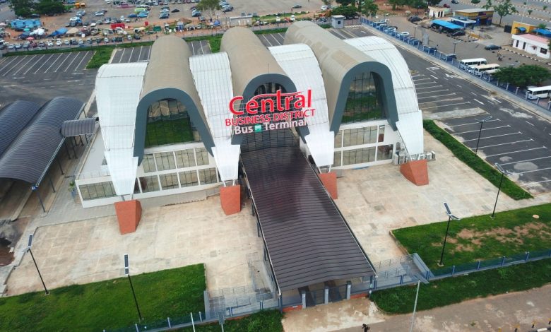 Abuja Bus terminal - The Times of Abuja Aerial view of a modern bus terminal with three curved white arches and a covered ramp, signage reads 'Central Business District Bus Terminal'.